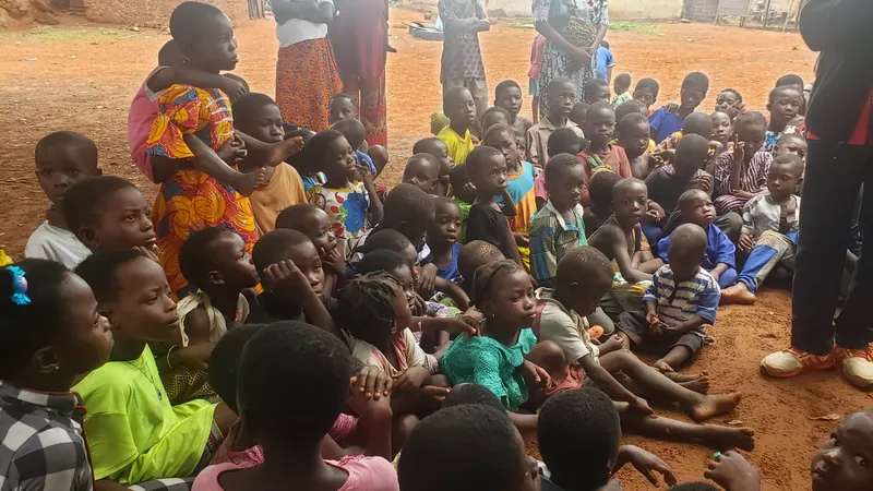 Un grupo grande de niños y adultos reunidos al aire libre para un evento de Dorcas Foundation.