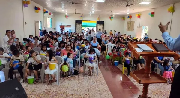 Una reunión comunitaria dentro de un salón con filas de sillas.