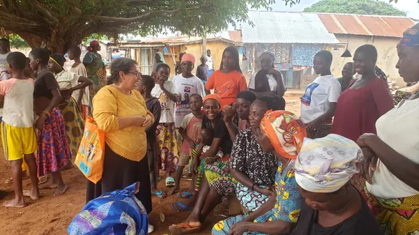 Una multitud de niños y adultos en un evento al aire libre de Dorcas Foundation.