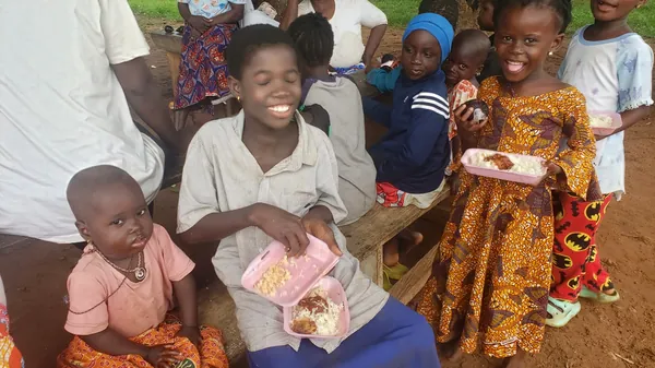 Niños sonriendo mientras comen en un evento de Dorcas Foundation.