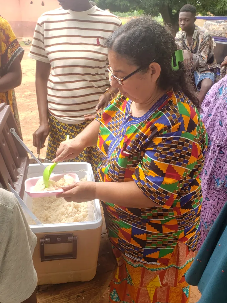 Una voluntaria sirviendo comida a un niño en una entrega de alimentos de Dorcas Foundation.